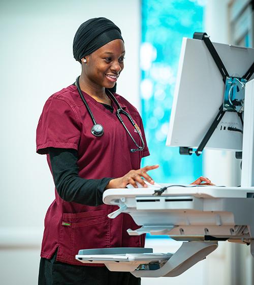 A student practices at a nursing station.