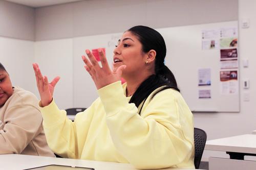 An IACD student in a yellow sweater practices sign language.