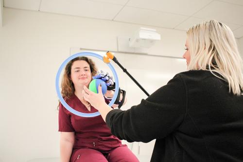 Two OT students practice movements with a ball through a hoop.