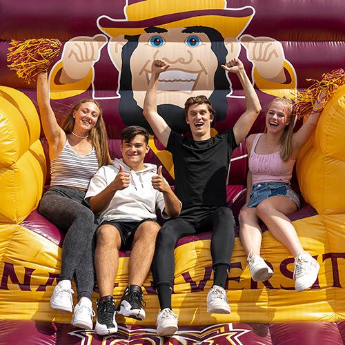 Four Students from the class of 2027 sit in the blow up chair.