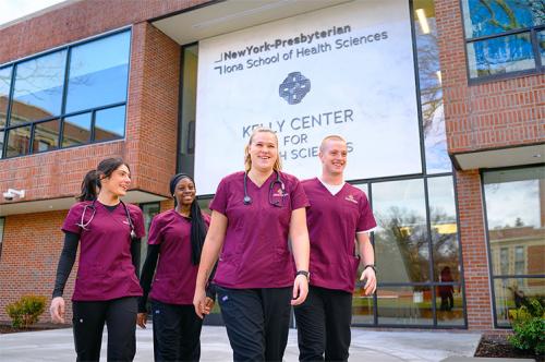 Four students walking by the Kelly Center for Health Sciences.