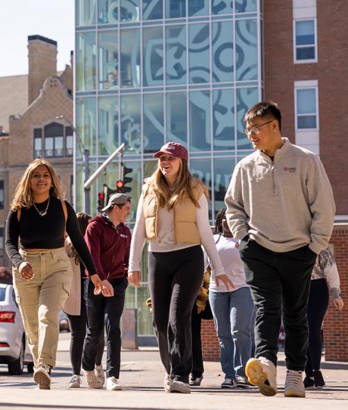 Three students enter campus through the north avenue entrance.