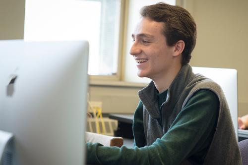 A student works in the computer lab and smiles.