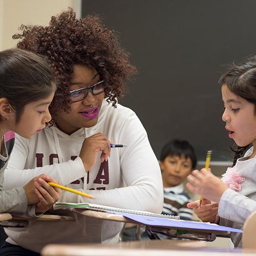 An education student works with two young school children.