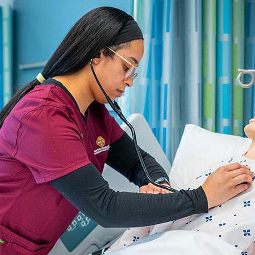 Three nurses in the simulation lab work with mannequins - 500x500