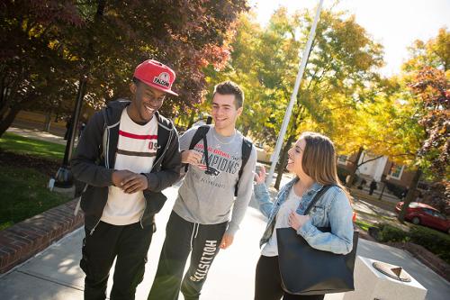 Three high school students walk and laugh near the quad.