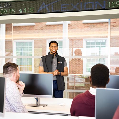 A student presents in front of the stock ticker in the LaPenta School of Business. 