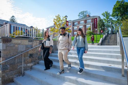 Three students walk down the steps of the Murphy Green on a sunny day.