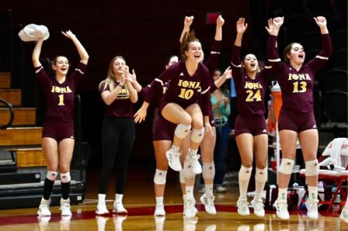 Volleyball team cheers on sideline.