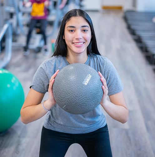 A student exercises with a medicine ball.