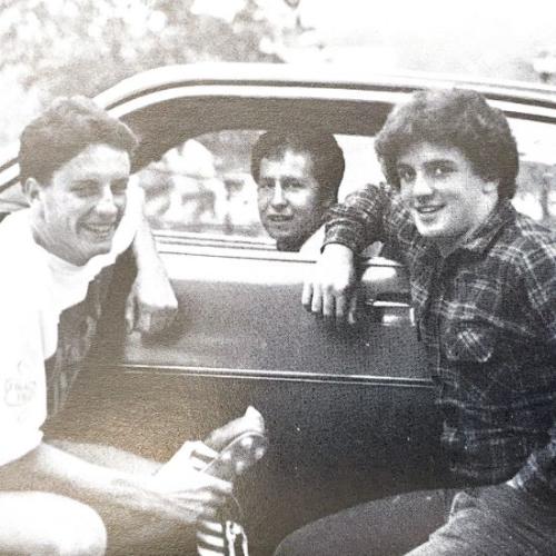 Students gathered in front of car for a photo on campus.