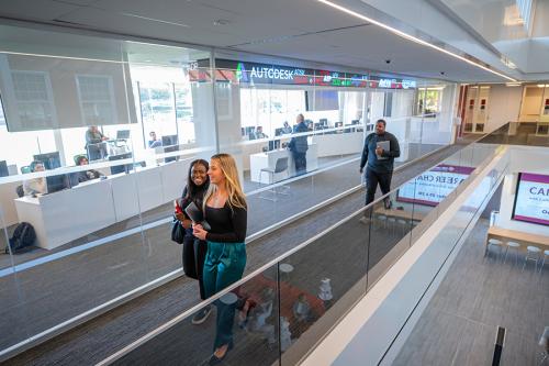 Students walk down the hallway of LSB with the ticker in the background.