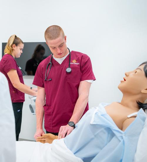 A nursing student practices taking blood pressure on a mannequin.