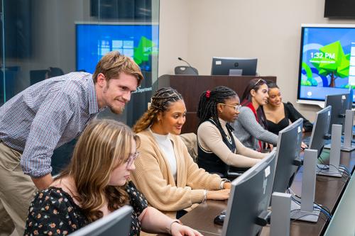 Graduate students work together at computer terminals.