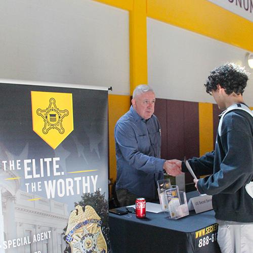 A student shakes hands with a recruiter from the Secret Service at the Career Fair.
