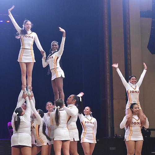 The cheer team performs two pyramids and smiles.