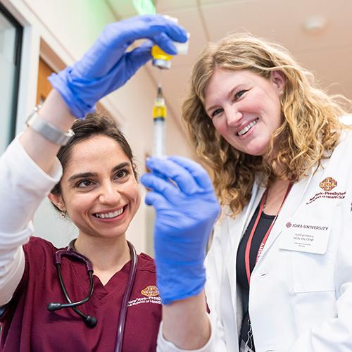 A nursing student and a professor practice filling a syringe.