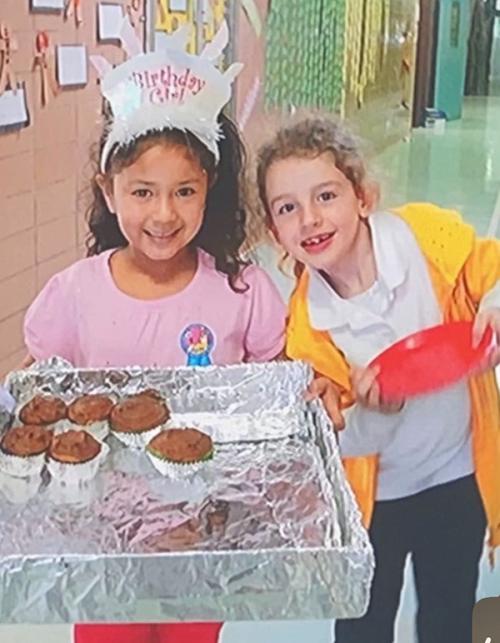 Lelia and Grace handing out birthday cupcakes in third grade.