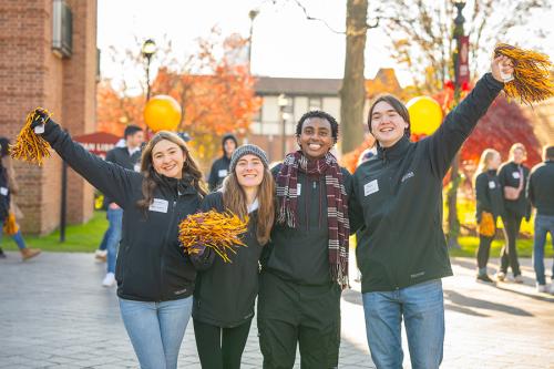 Gael guides smile and wave pom-poms and welcome students on campus.