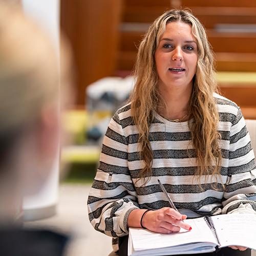 An education student talks with someone and takes notes.