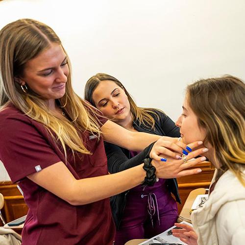 Three CSD students practice on each other.