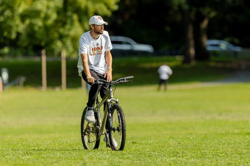 An athletics coach on a bike in a field.