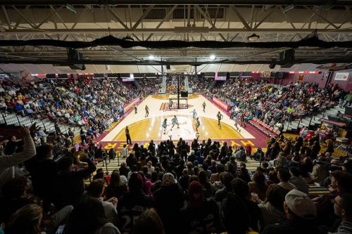 A packed Hynes Athletic Center is filled with fans watching a basketball game.