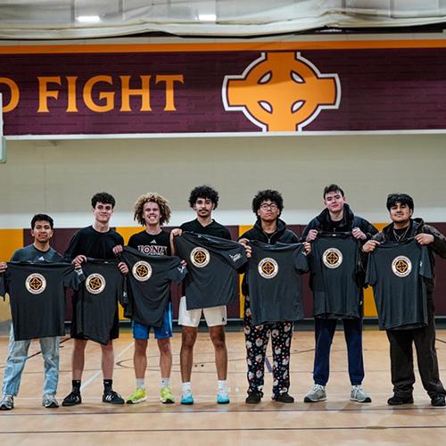 The intramural soccer team holds up their t-shirts.