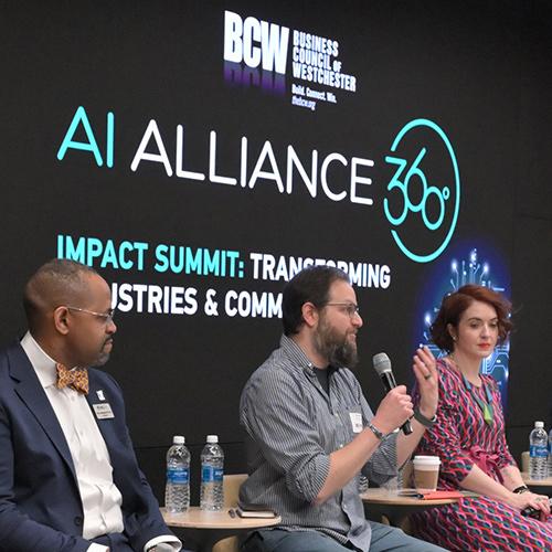 Rob Kissner of Iona University speaks at a microphone during the "AI Alliance 360° Impact Summit" panel, flanked by fellow panelists on a stage with a digital backdrop.