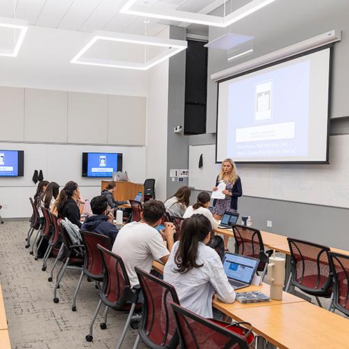 A professor teaches students in a nursing classroom.