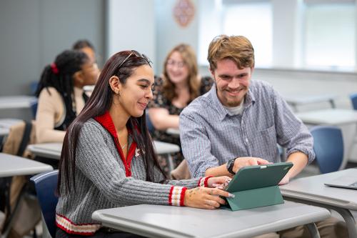 Two graduate students work together in the classroom.