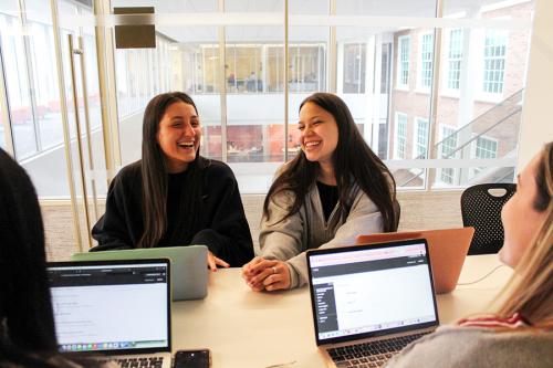 Two students study together and smile.