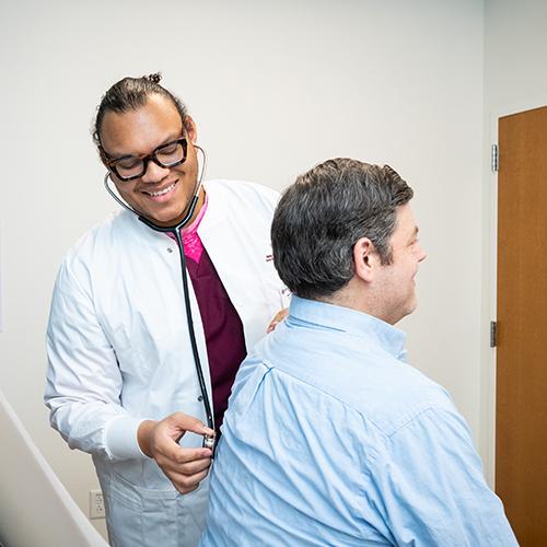 An FNP student practices listening to a patient's lungs.