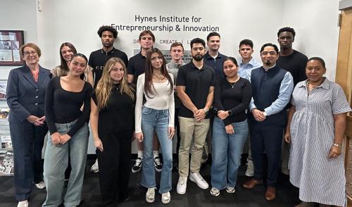 A group of Iona University students and faculty pose for a photo in front of the Hynes Institute for Entrepreneurship & Innovation sign.