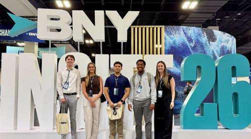 Five attendees pose together in front of a large BNY Insite 26 display sign at the Gaylord Rockies Resort in Aurora, Colorado.