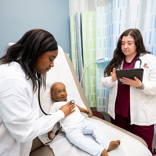 Iona nursing students practice with the stethoscope on a mannequin.