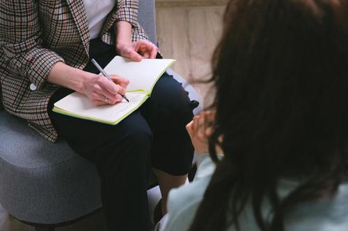 A mental health counselor takes notes during a session.