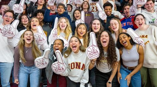 Students wave foam fingers and cheer at a game.