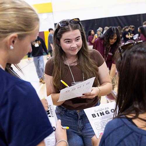 Students play ice-breaker bingo at a mixer event.