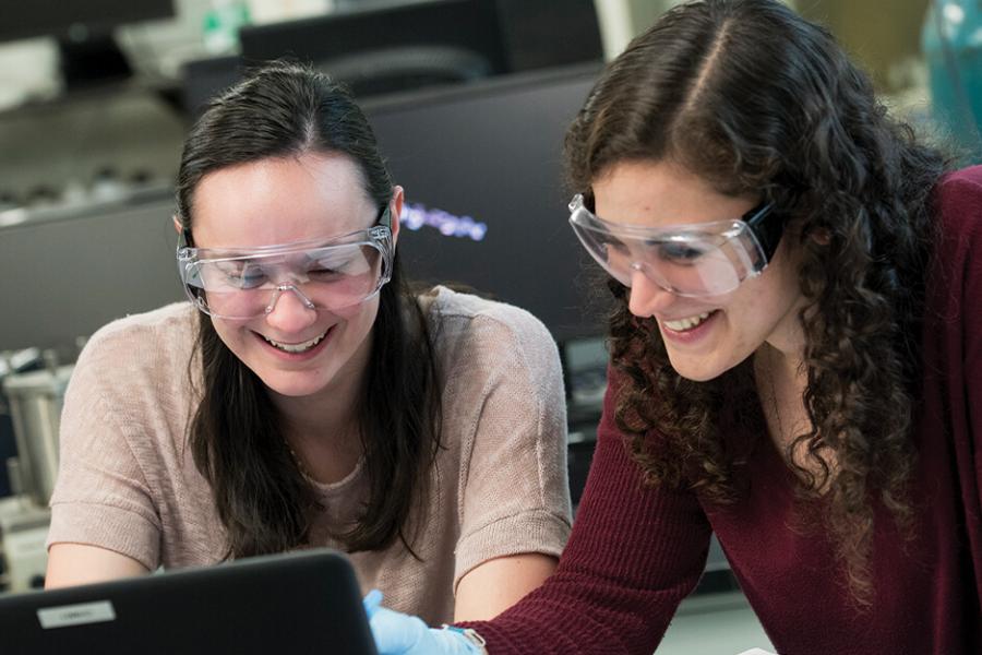 Two female students work in a lab at a computer.