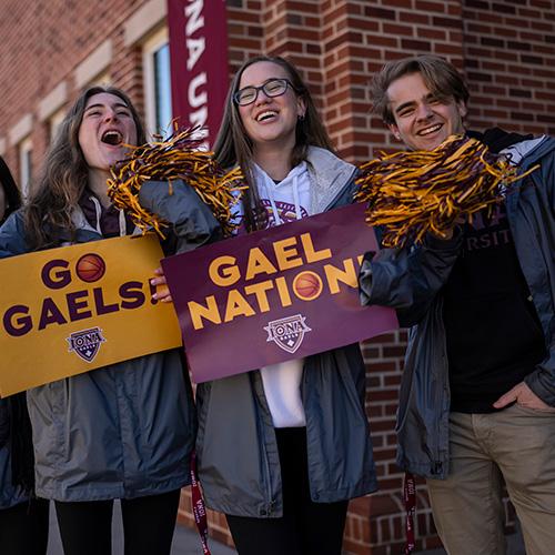 Three Gael Guides cheer and hold Go Gaels signs.